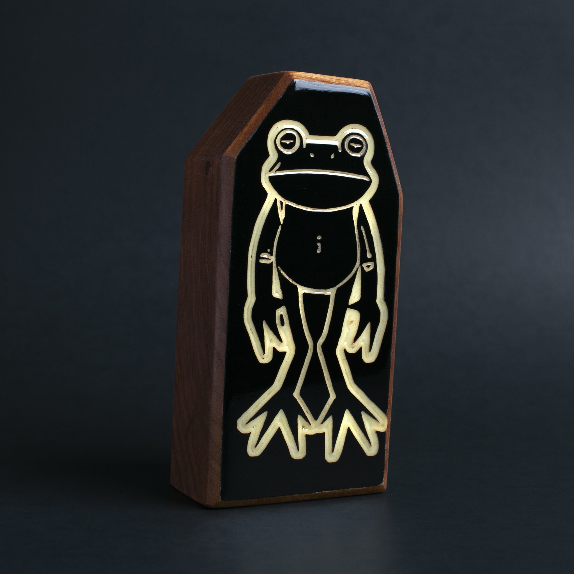 Floopfin handcrafted cherry wood talisman front view with glow-in-the-dark accents against a dark background